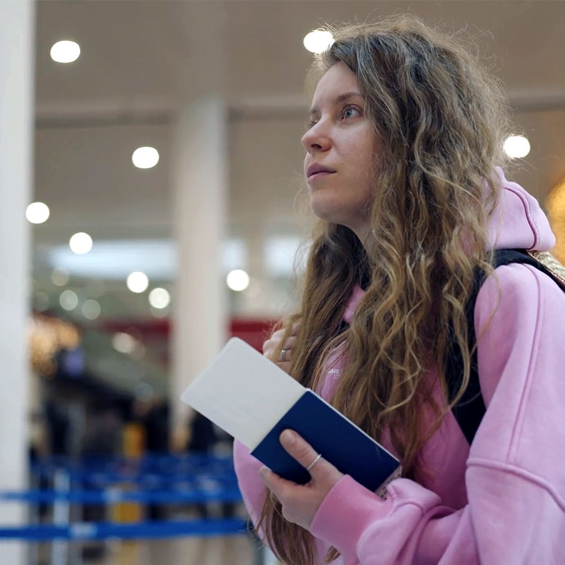 Air General Traveler Services concierge assisting young travelers in a busy summer airport terminal